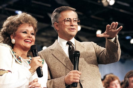 Bakker and Tammy Faye Bakker standing side by side holding microphones.