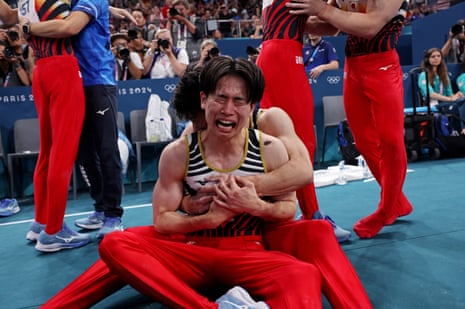 Kazuma Kaya of Japan is overwhlemed as he celebrates with his teammates after winning gold in the men’s artistic gymnastics final.