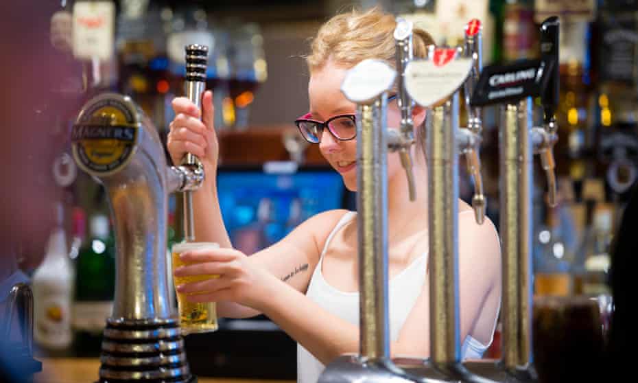 a young woman pours a pint of cider in a pub