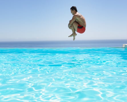 a man jumps into an infinity-style pool