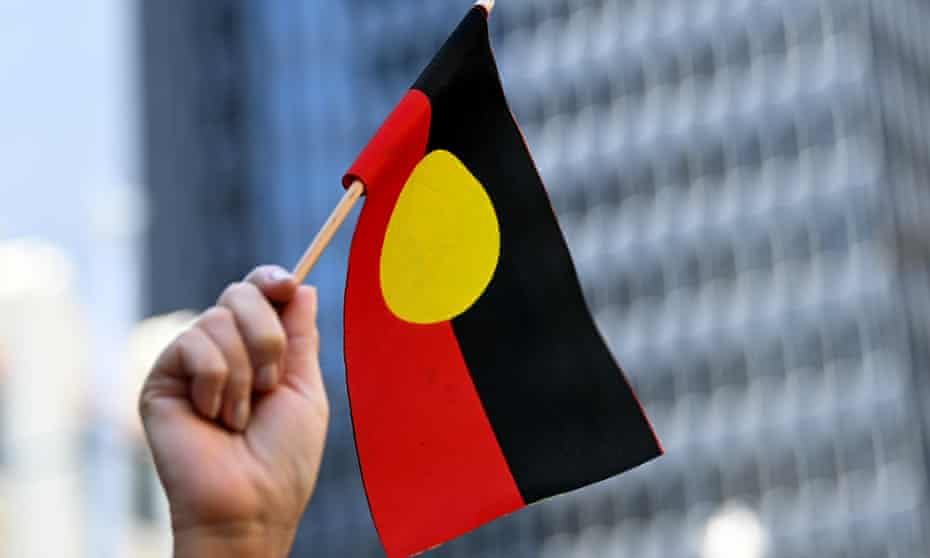 A hand waves the Australian Aboriginal flag