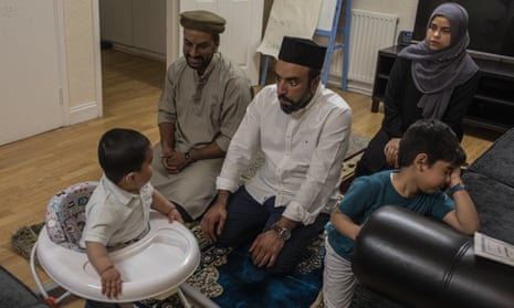 Imam Raza Ahmed pulls a face at his son, Daud, as the family pray at their home in London during Ramadan