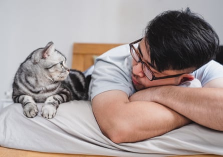 Man lying on bed with his cat, looking at each other