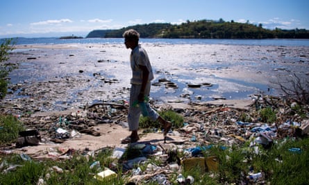 A man walks along the shoreline of the polluted waters of Guanabara Bay.