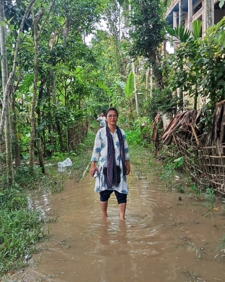 An Indian woman standing in flood water, which reaches her mid calf