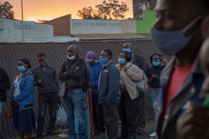 People wait in line for public transport to ferry them home after work