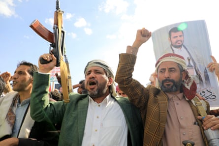 Yemeni men brandish their weapons and hold up portraits of Houthi leader Abdul Malik al-Houthi during a protest in solidarity with the Palestinian people.