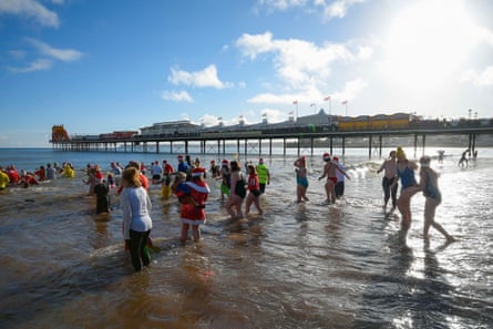 People hurrying into the sea on a cold day in Devon for a Christmas swim
