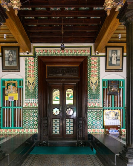 A carved teak door in a wall decorated with patterned tiles