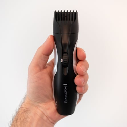 The writer’s hand is seen holding a black and silver beard trimmer