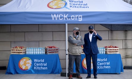 José Andrés and Joe Biden, wearing masks, standing in front of a World Central Kitchen stall