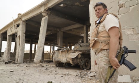 A Russian soldier stands in front of a destroyed tank factory operated by Isis militants.