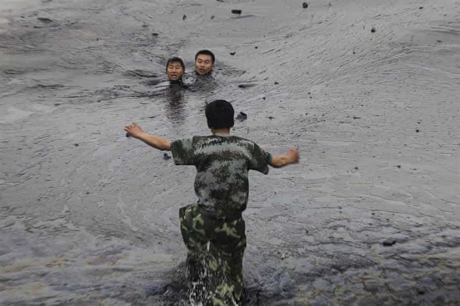 A antheral   attempts to rescue 2  lipid  firefighters, Zhang Liang and Han Xiaoxiong, struggling successful  heavy   lipid  slick, 2010