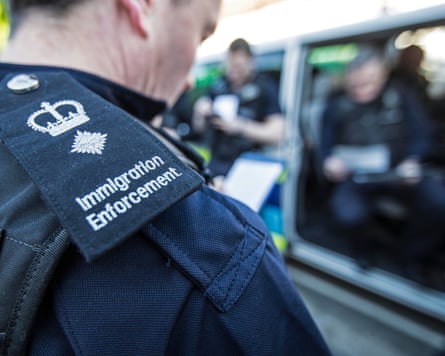 Immigration officers in uniform listen to a brief