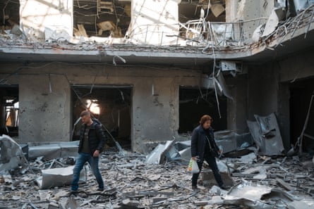 People walking through debris in building.