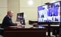 Vladimir Putin at his desk in front of a videoconference meeting screen