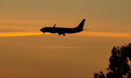 a plane in silhouette comes into land at dusk