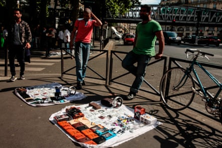 People walk past men selling items in a street in La Chapelle