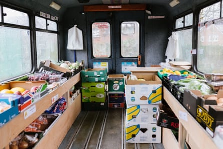 Interior of minibus, which has no seats, showing boxes of fruit and veg lined up to each side.