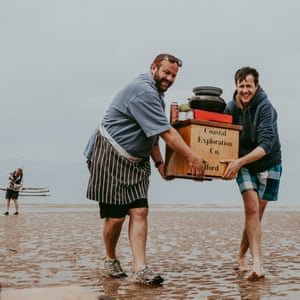 Chef Charlie Hodson and author Patrick Barkham move their cooking utensils to another part of the sandbank as the tide comes in. Norfolk, UK.