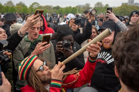 Man in red, green and gold knitted hat and dreadlocks lights up a giant spliff