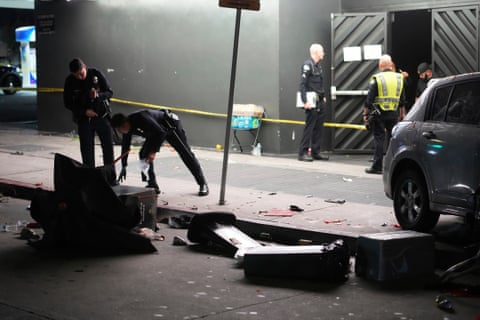 officers inspect debris from a car crash on the street outside a club at night
