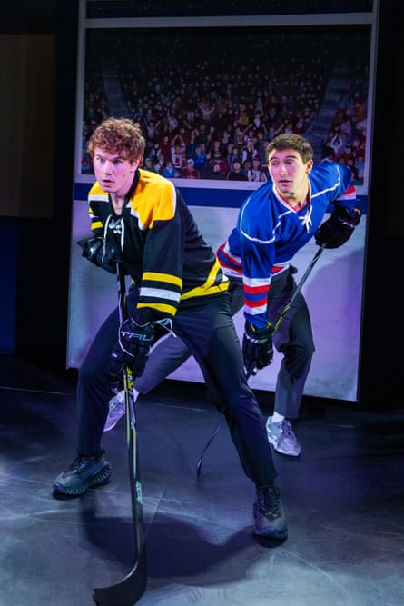 Two men pretend to play ice hockey on stage.