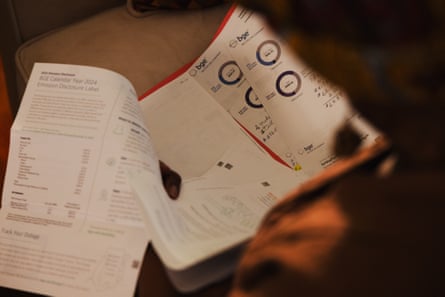 A person’s silhouette is seen in the foreground as her hands sort through electric bills