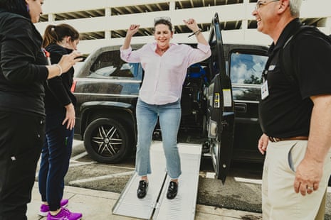 A woman jumps for joy on a car ramp surrounded by three people