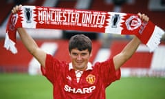 Roy Keane holds up a Manchester United after signing in 1993