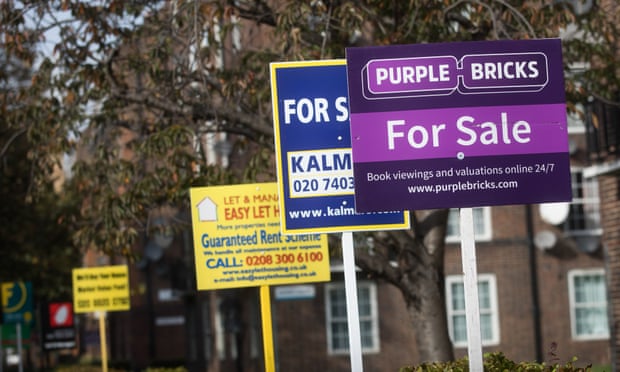 Estate agents’ boards advertising homes for sale stand near a block of flats in London