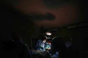 A doctor performs surgery under the illumination of a battery-powered light during a power outage