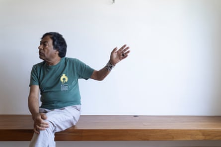 A man sits on a bench holding out one arm