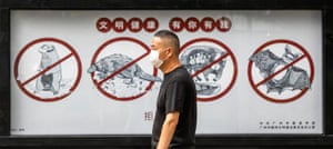 A man walks past a poster warning people that consuming wildlife is illegal, in Guangzhou, Guangdong province, China.