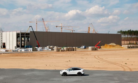Musk touring the site in his white Tesla car.