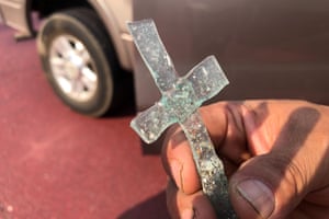Artemio Guterrez, a single father of four, holds a cross made of two pieces of glass that melded together during the intense heat from the wildfire that swept through Talent, Oregon.