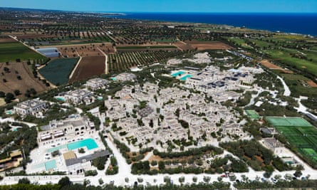 Aerial view of a village-sized resort comprising mainly villas built in pale stone