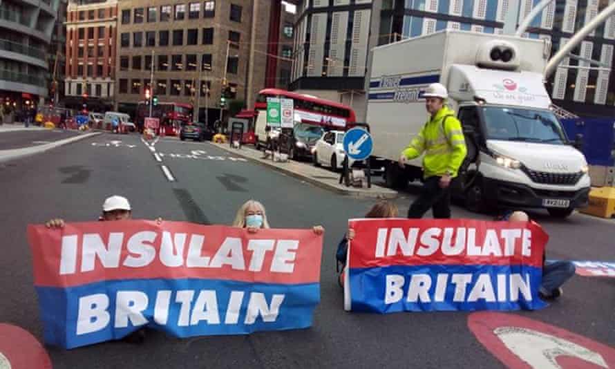 Activists sitting across a road holding 'Insulate Britain' banners