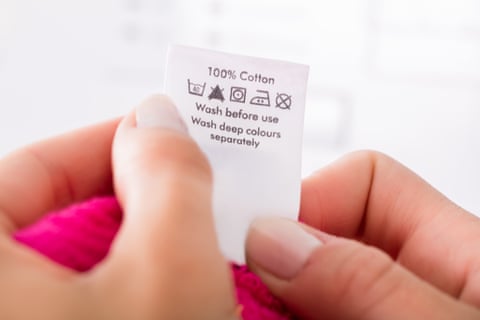 Close up of hands holding a garment care label.