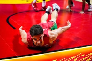 Malaga, Spain. A basketball player with a goaty and wearing the red and green of Portugal lies on his tummy with his arms sticking our to the side on what looks to be a red-painted key section of a basketball court