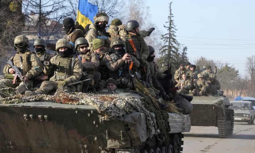 Ukrainian soldiers ride a tank through the town of Trostyanets.