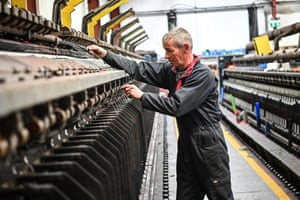 A worker threads yarn through a loom