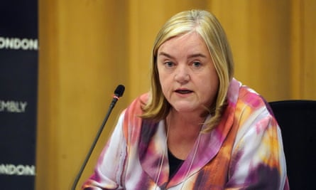 Louise Casey sitting at a table with a microphone, as though at a press conference