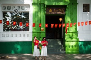 Women wear red T-shirts bearing a yellow star while standing in front of a green doorway with bunting in the same design hung across it