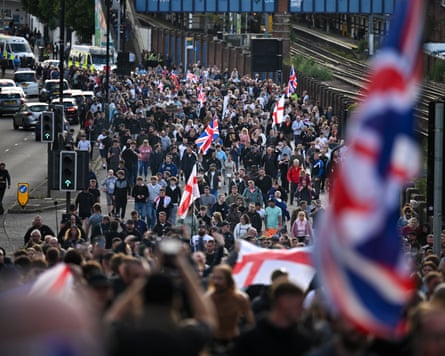 A crowd marches along a road carrying flags