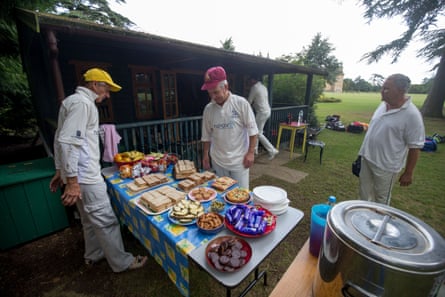 Players gather round a table laden with sandwiches, cakes and biscuits