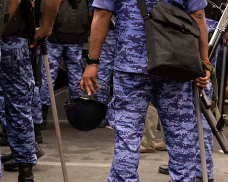 rear cropped view of members of India's Rapid Action Force with sticks and firearms visible.