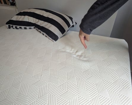 A Panda Hybrid Bamboo Mattress with a dent in it and man pointing to the dent