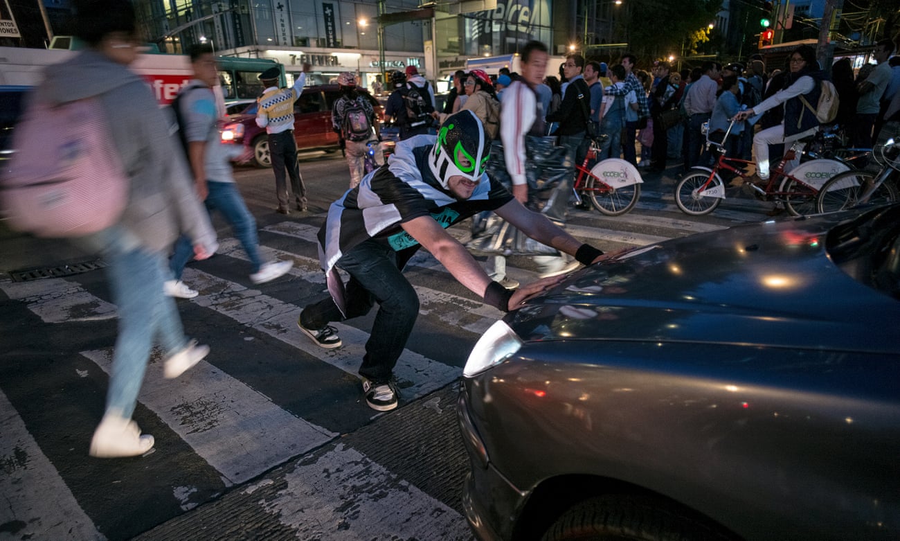 Masked campaigner Peatónito pushes back a car that has strayed on to a pedestrian crossing in Mexico City.