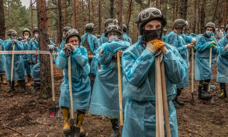 Police, prosecutors, forensic doctors and journalists gather at a mass grave containing more than 440 bodies discovered in Izium after the retreat of Russian forces last year.